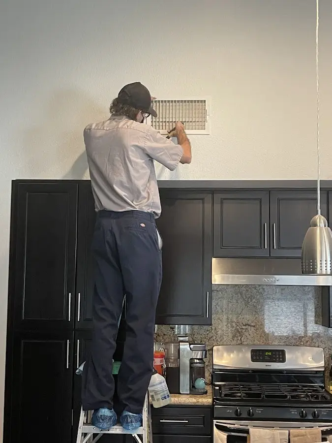 Technician inspecting an air vent during HVAC service in North Branch